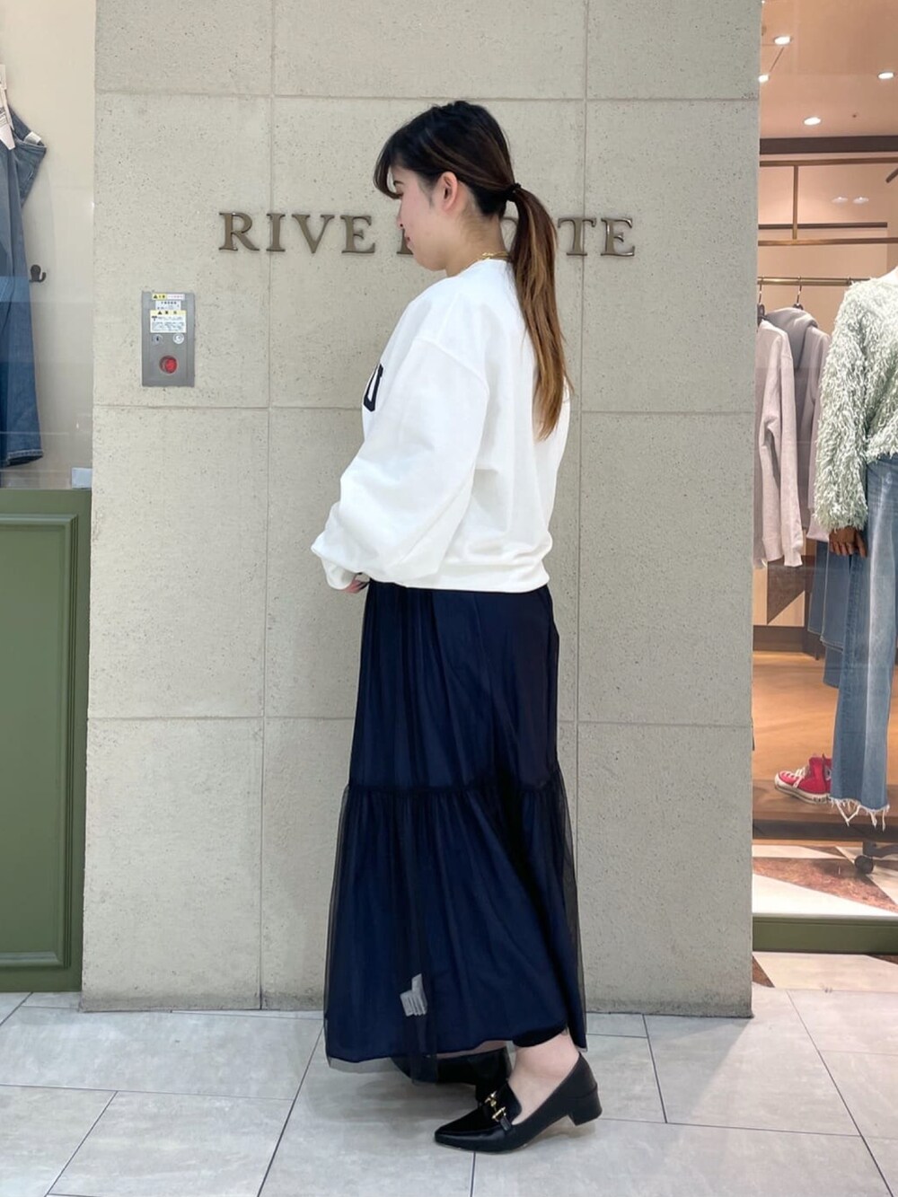 ホワイト系のスウェット、ブラック系のスカート、ブラック系のローファーを着用したレディースの冬コーディネートの2枚目の写真