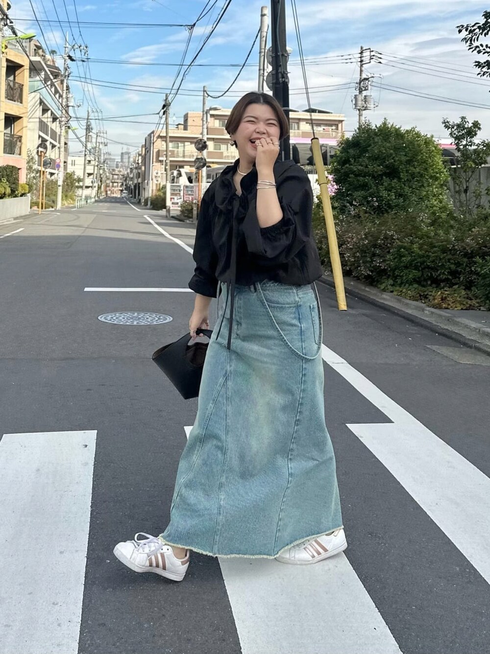 ブラック系のシャツ/ブラウス、ブラック系のハンドバッグ、ブルー系のデニムスカートを着用したレディースの冬コーディネートの3枚目の写真