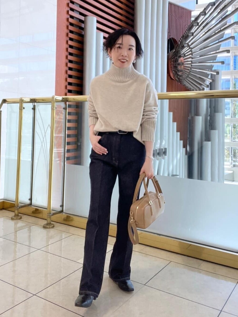 ベージュ系のニット/セーター、ベージュ系のその他アウター、ブルー系のデニムパンツを着用したレディースの秋コーディネートの2枚目の写真