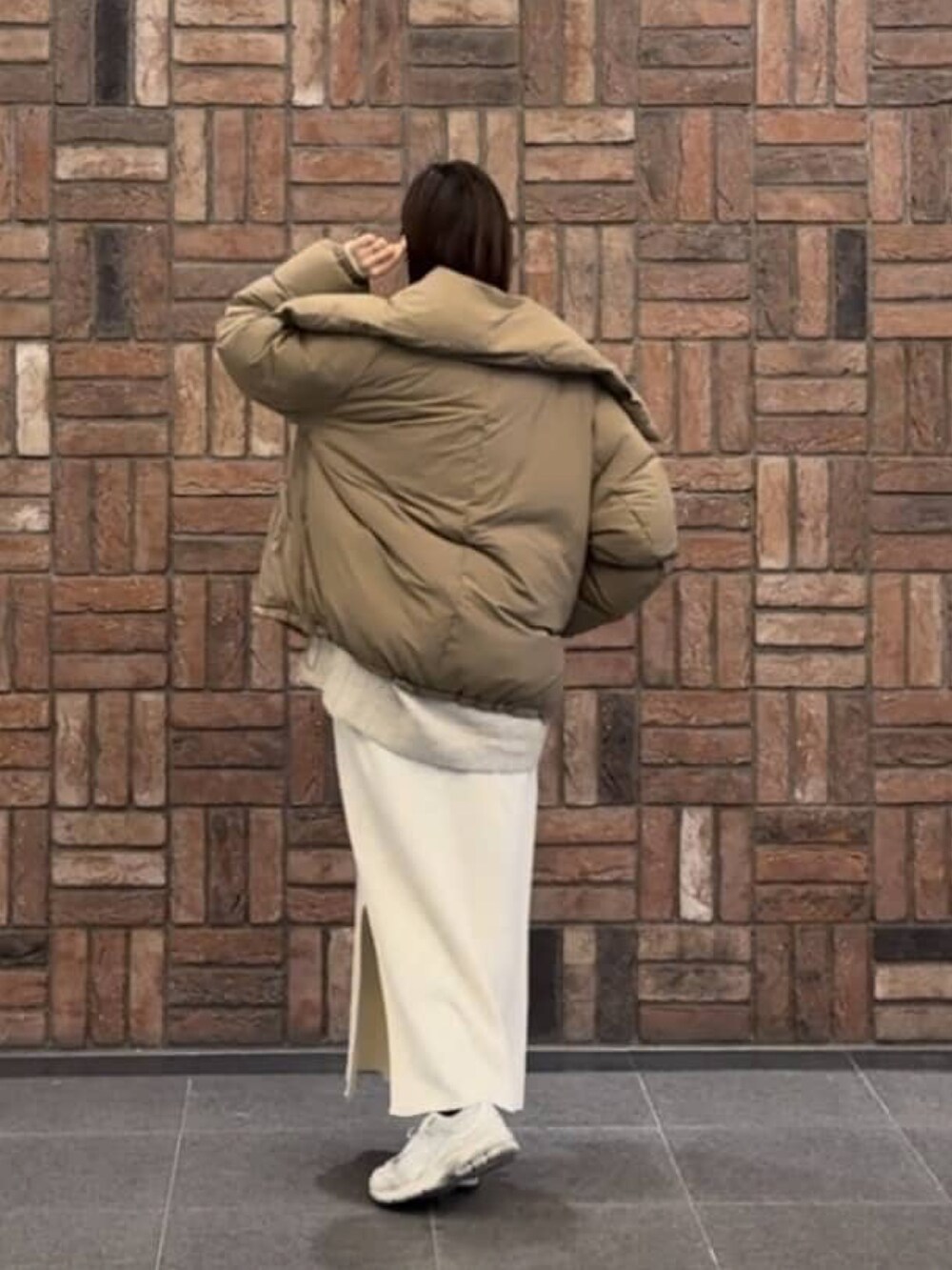 イエロー系のダウンジャケット/コート、ホワイト系のワンピース、ベージュ系のニット/セーターを着用したレディースの冬コーディネートの2枚目の写真