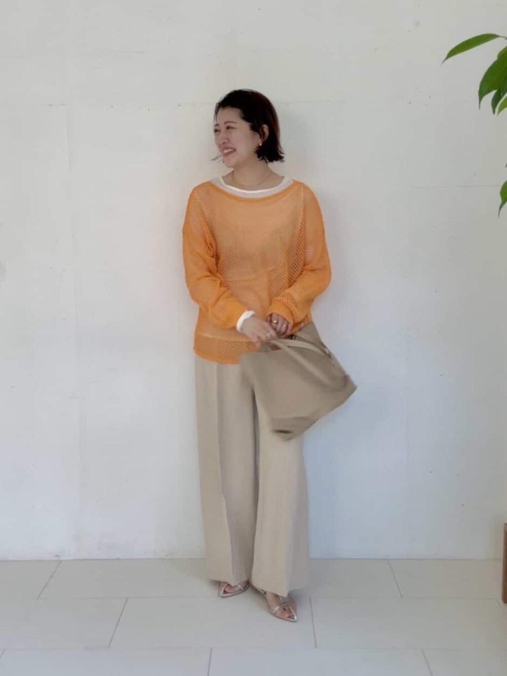 オレンジ系のニット/セーター、ベージュ系のその他パンツ、ベージュ系のトートバッグを着用したレディースの冬コーディネートの2枚目の写真