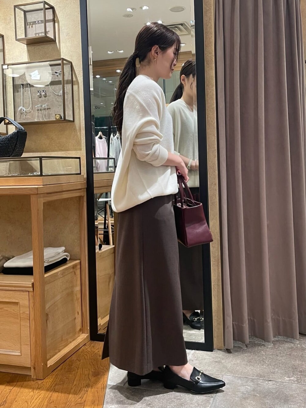 ホワイト系のニット/セーター、ブラウン系のスカート、ブラック系のパンプスを着用したレディースの冬コーディネートの2枚目の写真