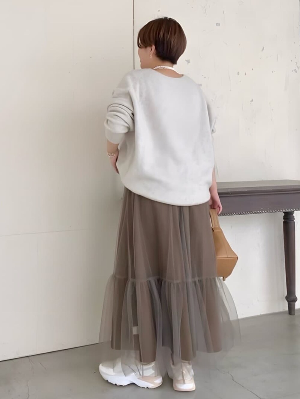 グレー系のニット/セーター、ブラウン系のスカート、イエロー系のハンドバッグを着用したレディースの夏コーディネートの2枚目の写真