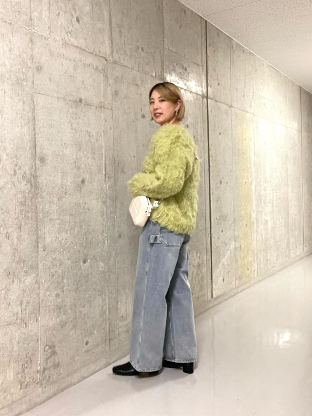 グリーン系のニット/セーター、ブルー系のデニムパンツを着用したレディースの冬コーディネートの5枚目の写真