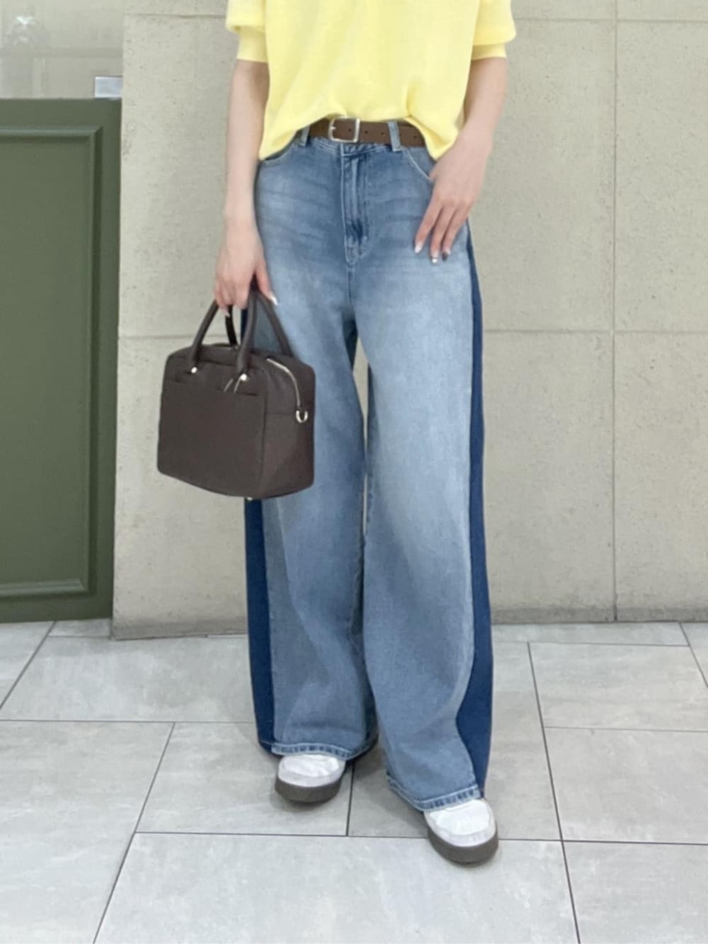 ブラウン系のボストンバッグ、イエロー系のニット/セーター、ブルー系のデニムパンツを着用したレディースの春コーディネートの7枚目の写真