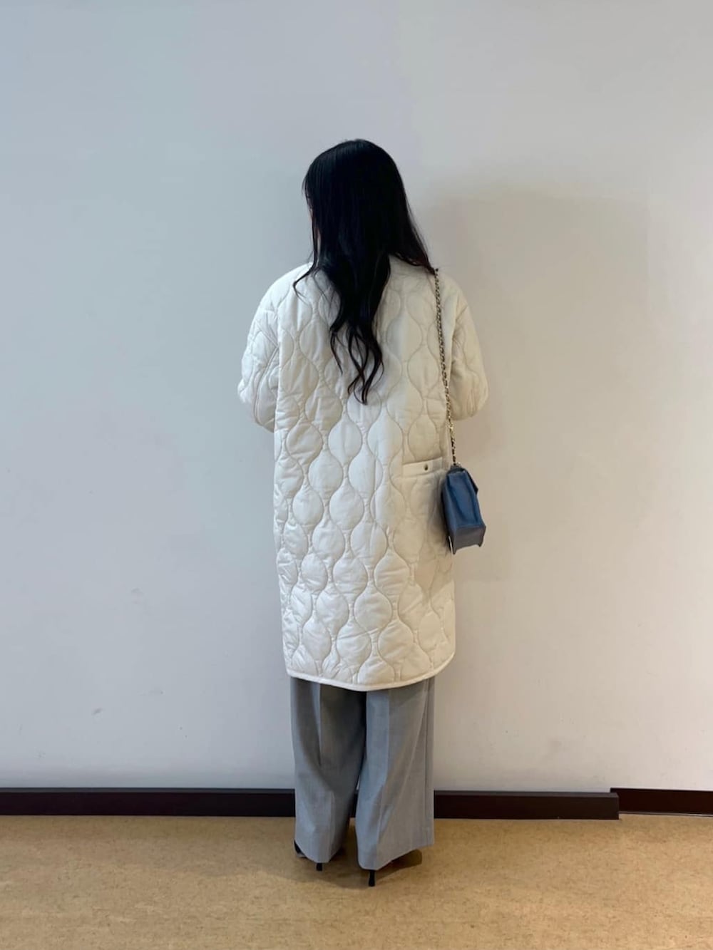 ブルー系のニット/セーター、ホワイト系のダウンジャケット/コート、ブルー系のハンドバッグを着用したレディースの冬コーディネートの3枚目の写真