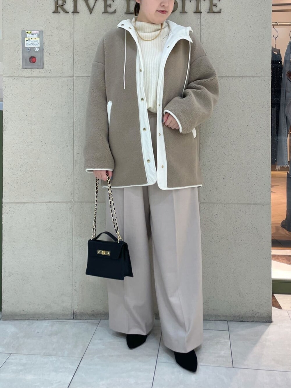 ブラック系のハンドバッグ、ベージュ系のその他アウター、ホワイト系のニット/セーターを着用したレディースの冬コーディネートの2枚目の写真