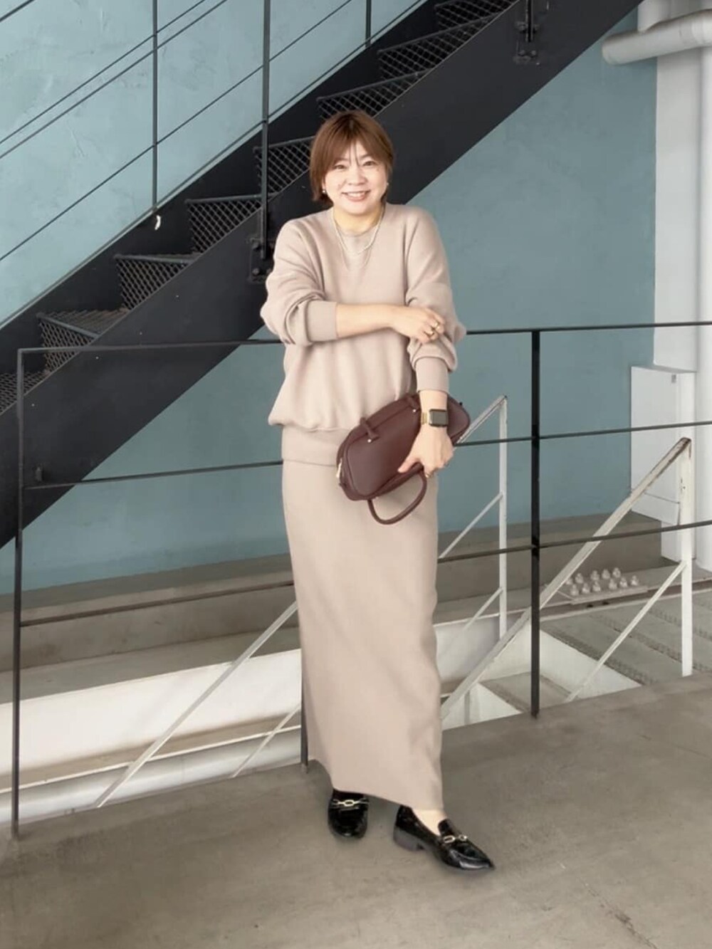 ブラウン系のショルダーバッグ、ブラウン系のニット/セーター、ブラウン系のスカートを着用したレディースの秋コーディネートの2枚目の写真