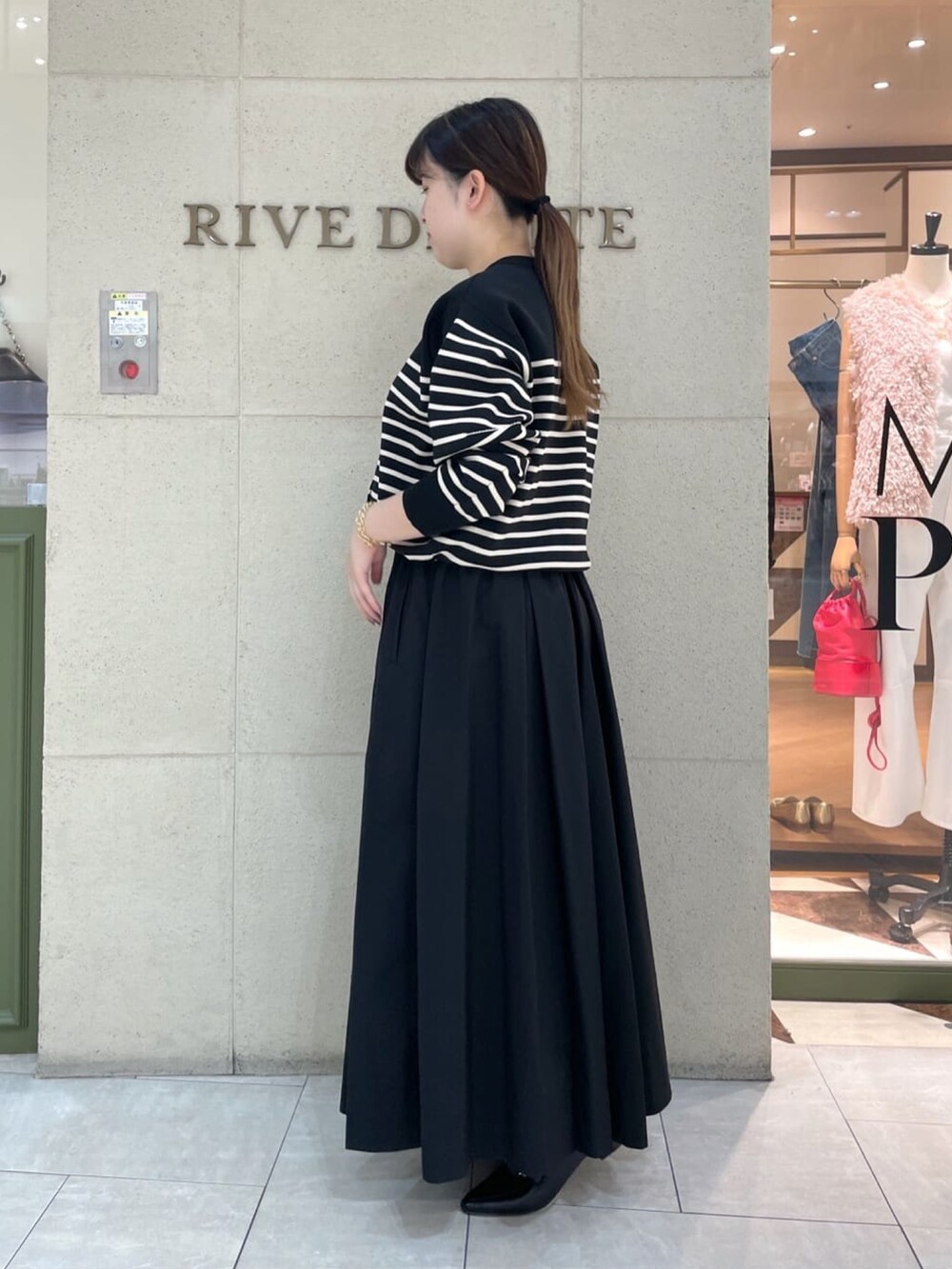 ブラック系のニット/セーター、ブラック系のスカート、ブラック系のローファーを着用したレディースの秋コーディネートの3枚目の写真