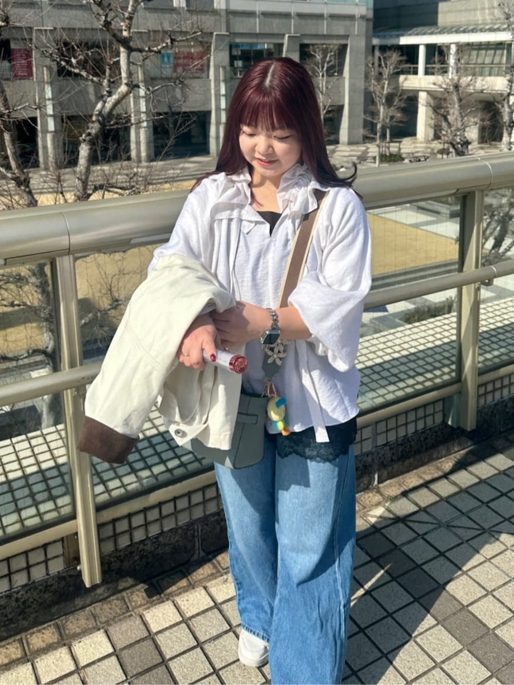 ブルー系のデニムパンツ、ブルー系のトートバッグ、ブラウン系のキャミソールを着用したレディースの春コーディネートの2枚目の写真