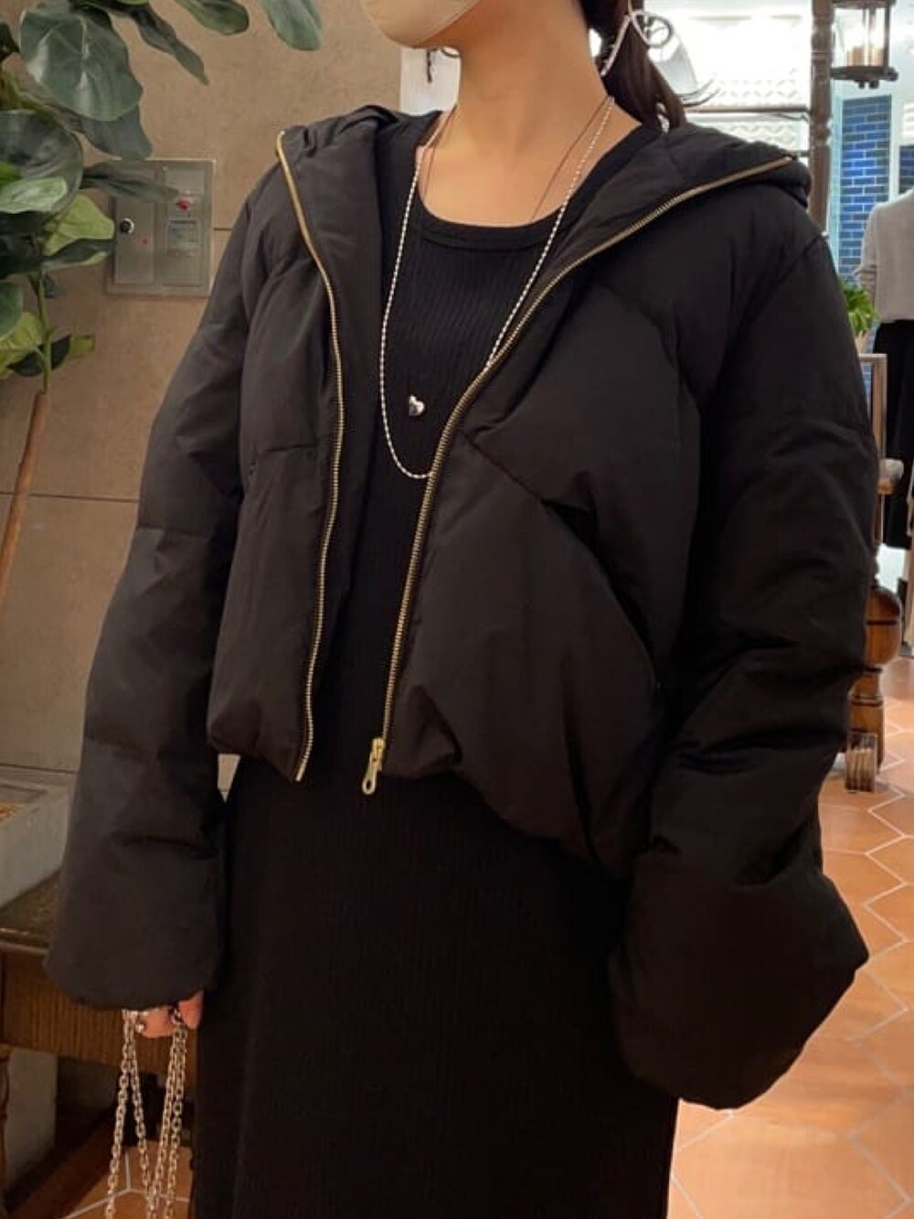 シルバー系のショルダーバッグ、ブラック系のワンピース、ブラック系のブーツを着用したレディースの冬コーディネートの3枚目の写真