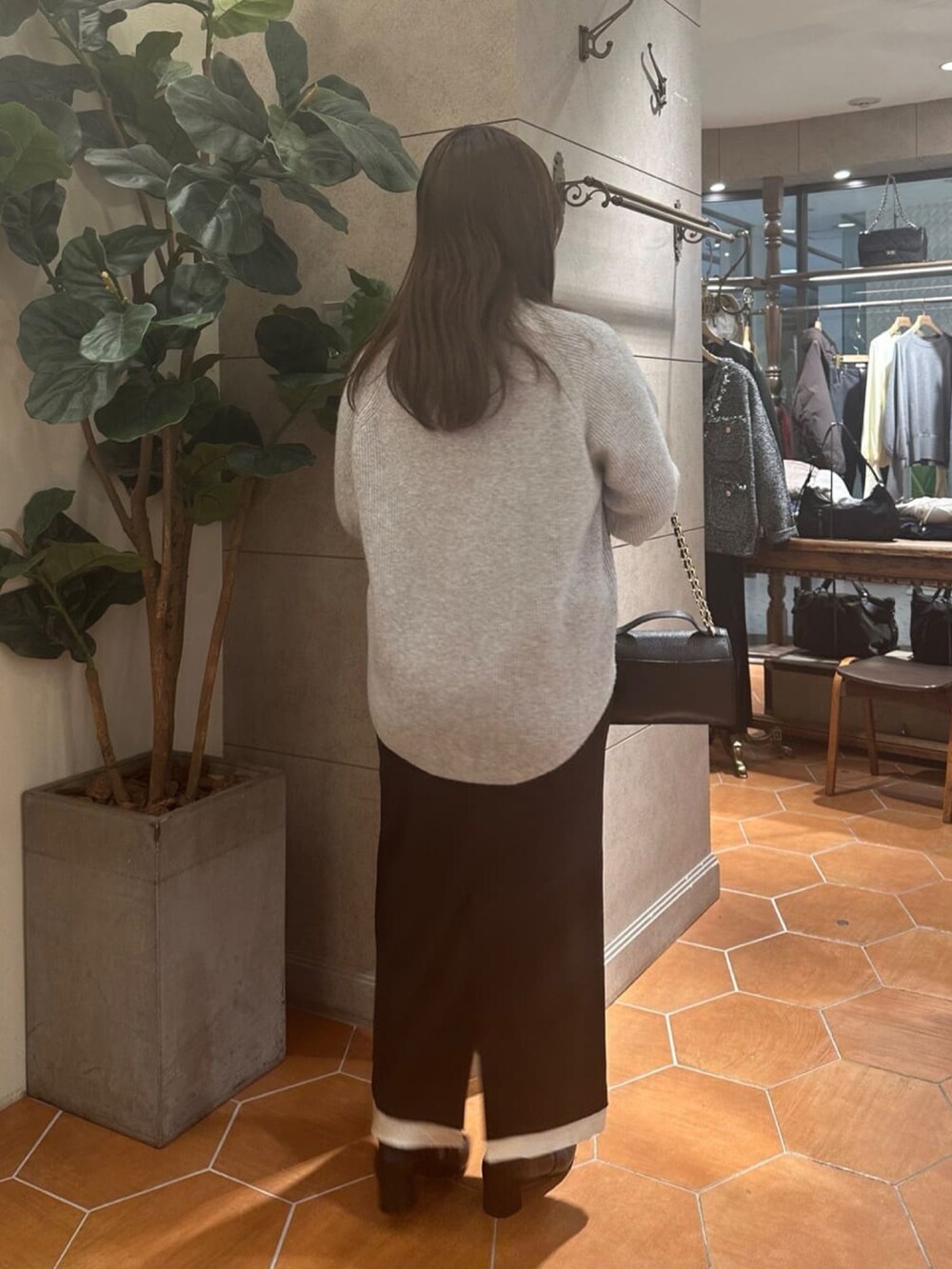 グレー系のニット/セーター、ブラック系のスカート、ブラック系のハンドバッグを着用したレディースの冬コーディネートの4枚目の写真