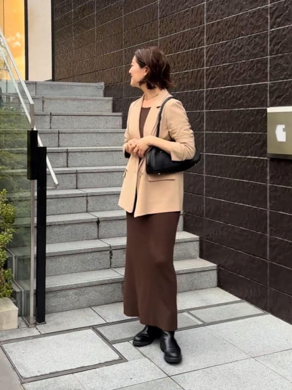 ブラウン系のワンピース、イエロー系のテーラードジャケット、ブラック系のショルダーバッグを着用したレディースの秋コーディネートの3枚目の写真