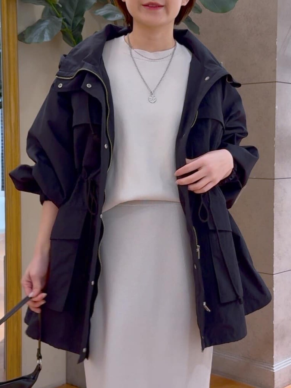 グレー系のニット/セーター、グレー系のスカート、ブラック系のマウンテンパーカーを着用したレディースの冬コーディネートの4枚目の写真