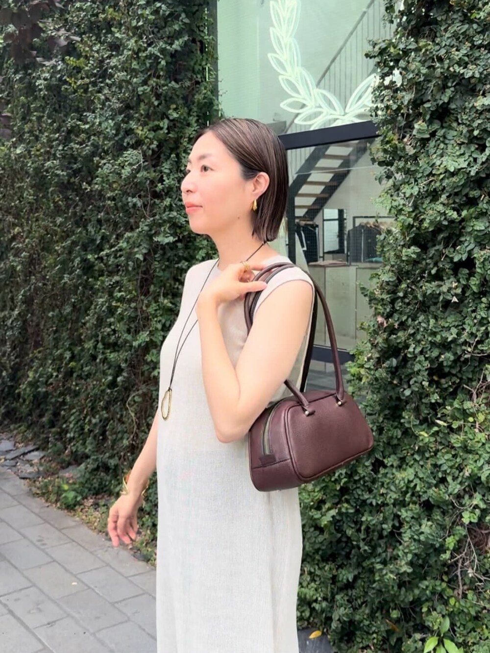 ブラウン系のショルダーバッグ、ベージュ系のワンピース、ブルー系のデニムパンツを着用したレディースの夏コーディネートの4枚目の写真