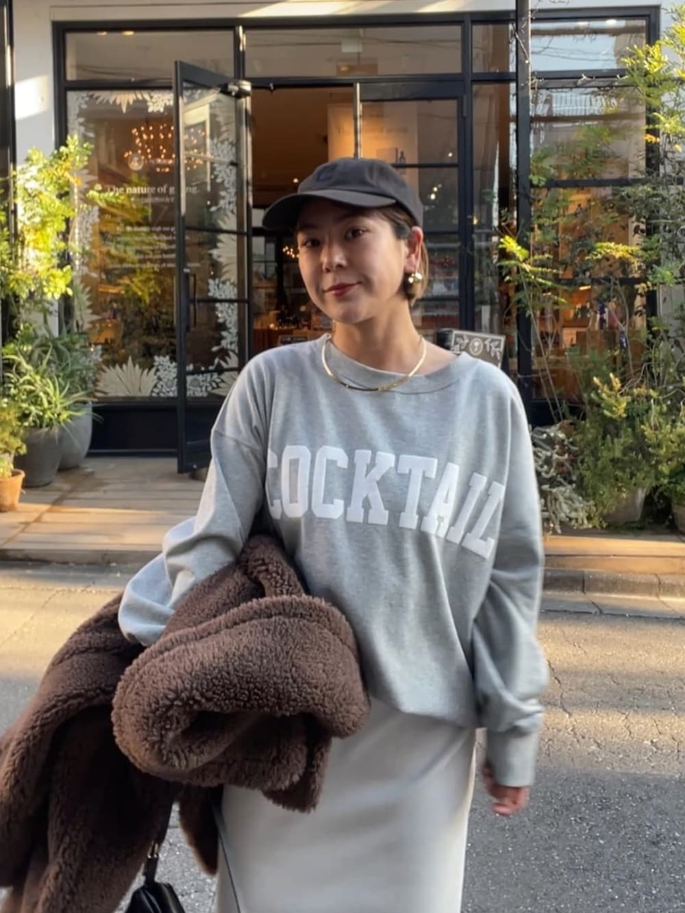 ブラウン系のスカート、ブラック系のショルダーバッグ、グレー系のスウェットを着用したレディースの冬コーディネートの3枚目の写真