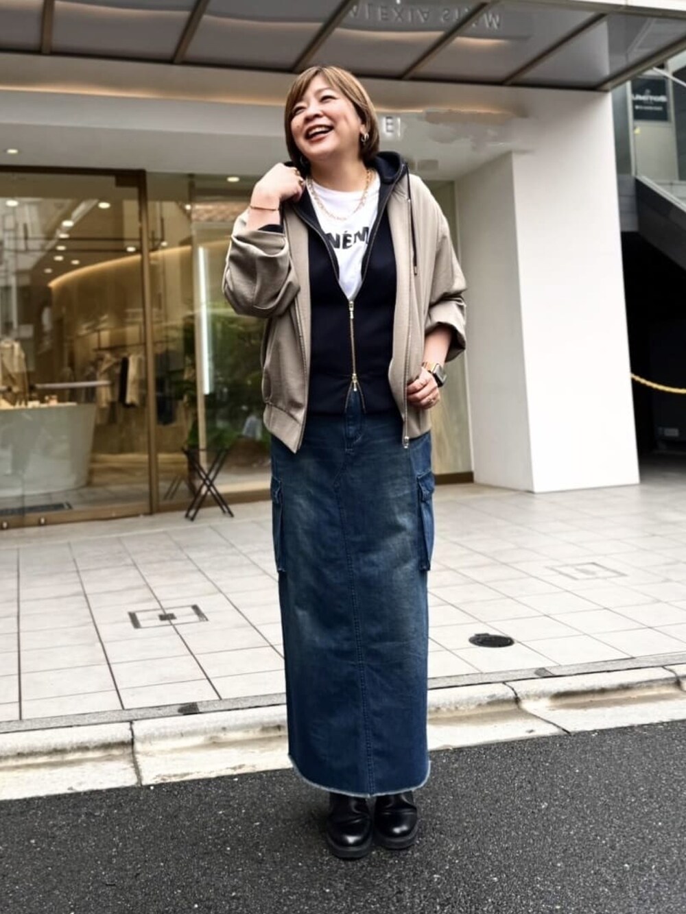 ブラック系のパーカー、ブルー系のデニムスカート、ブラック系のブーツを着用したレディースの秋コーディネートの3枚目の写真