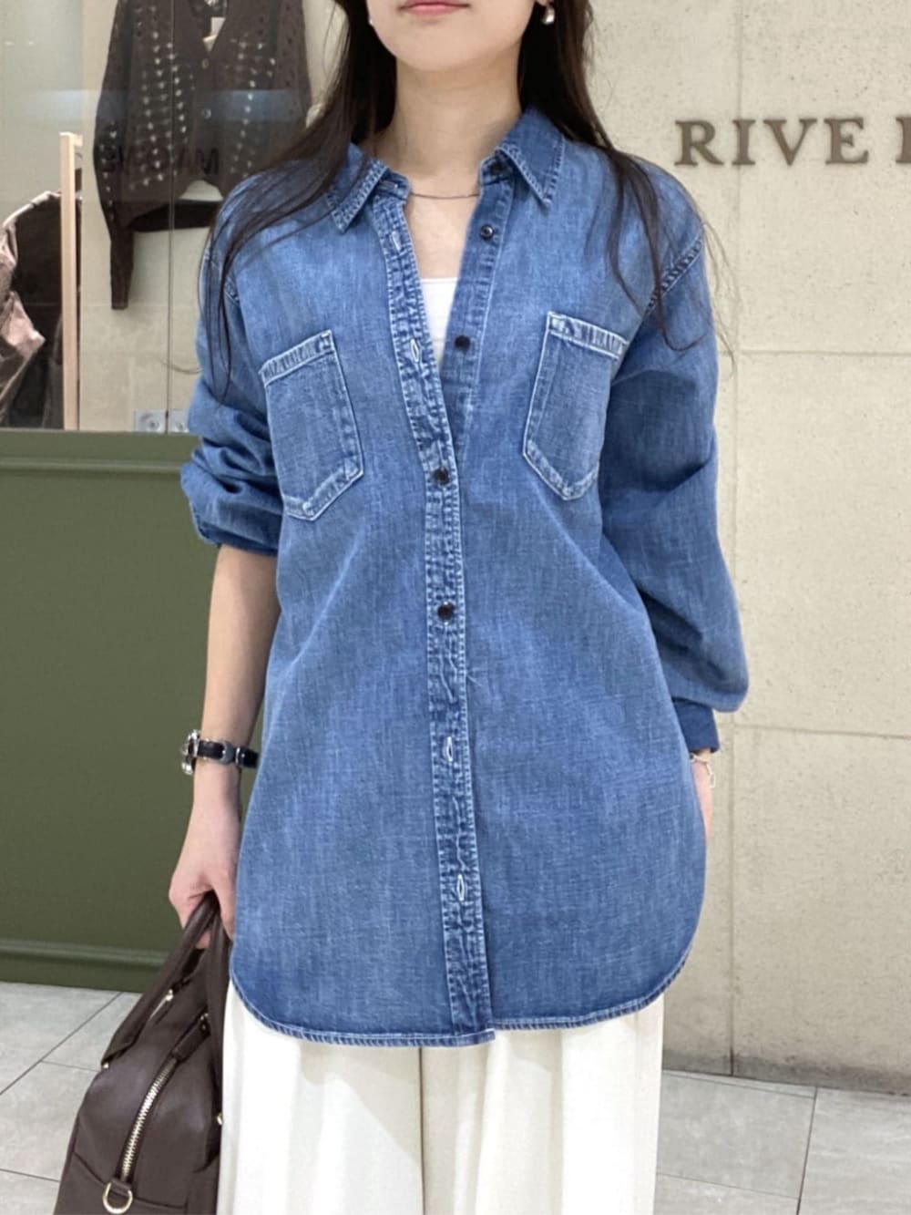 ホワイト系のスラックス、ブルー系のシャツ/ブラウス、ブラウン系のボストンバッグを着用したレディースの春コーディネートの4枚目の写真