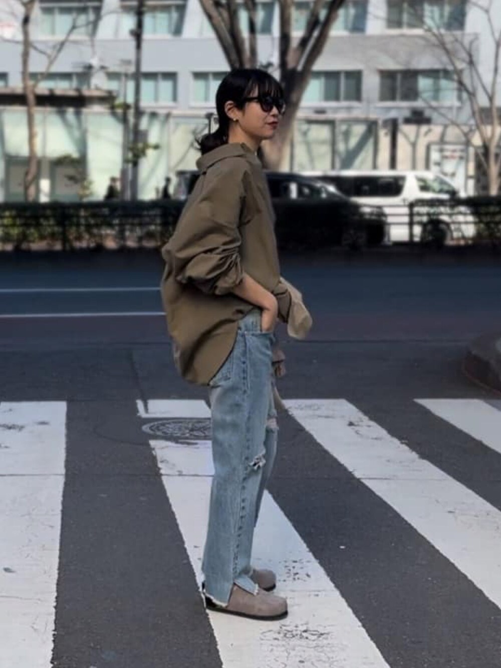 グリーン系のシャツ/ブラウス、グレー系のタンクトップ、ブルー系のデニムパンツを着用したレディースの春コーディネートの2枚目の写真