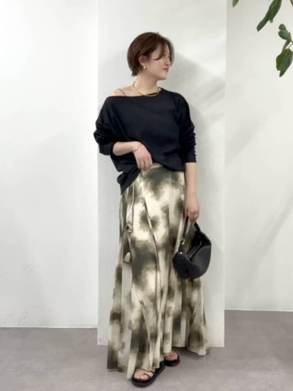 ブラック系のショルダーバッグ、ベージュ系のスカート、ブラック系のサンダルを着用したレディースの春コーディネートの2枚目の写真