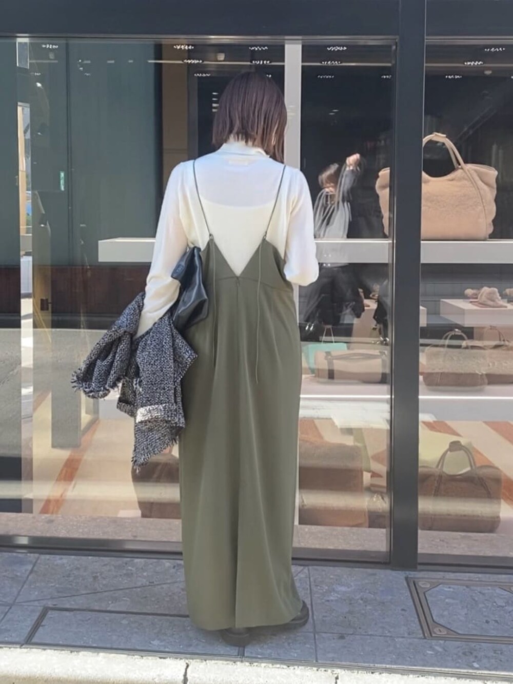 グリーン系のワンピース、ホワイト系のニット/セーターを着用したレディースの冬コーディネートの3枚目の写真