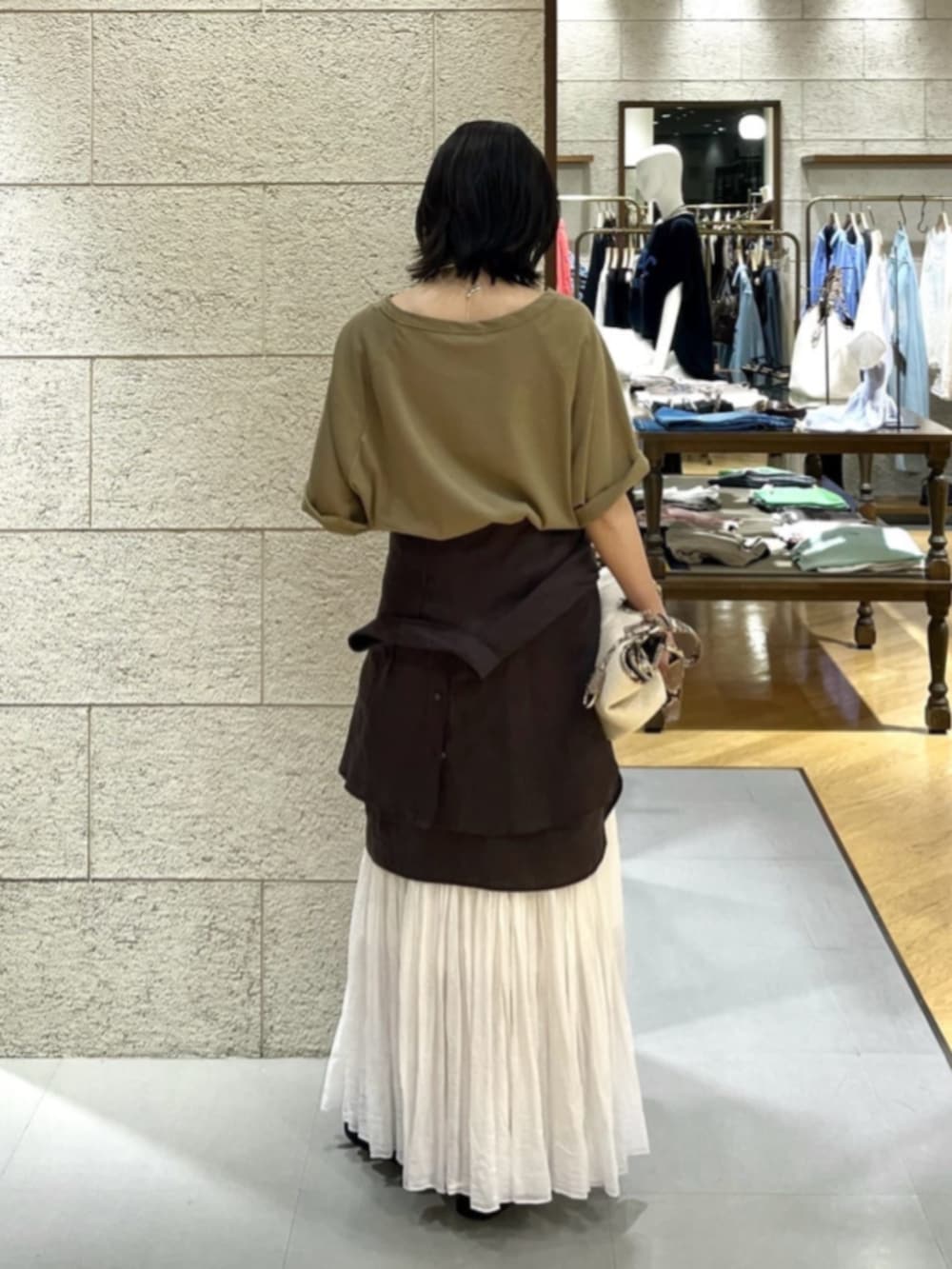 ブラウン系のシャツ/ブラウス、ベージュ系のハンドバッグ、ホワイト系のスカートを着用したレディースの夏コーディネートの2枚目の写真