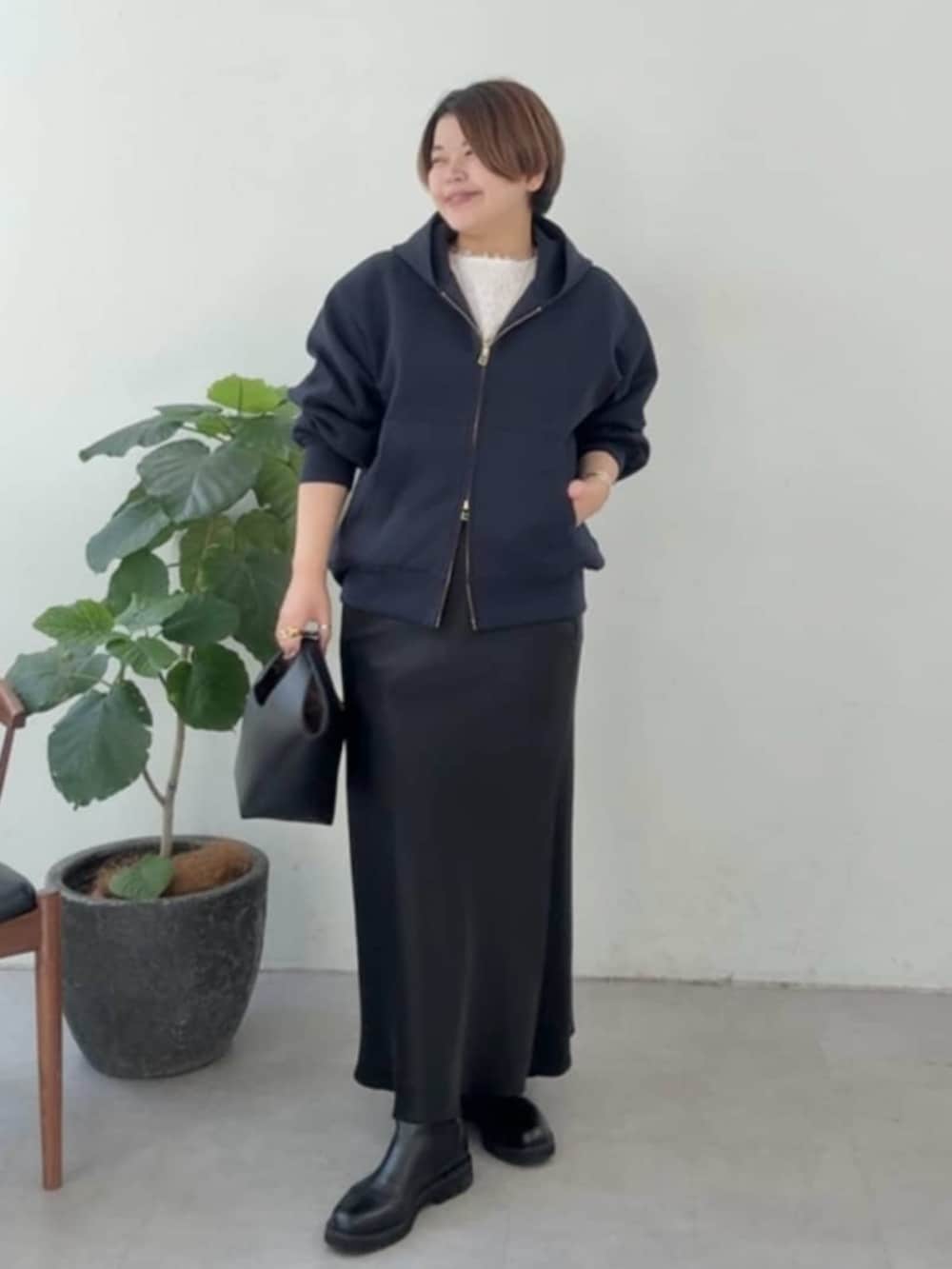 ブラック系のハンドバッグ、ブラック系のスカート、ブラック系のブーツを着用したレディースの冬コーディネートの5枚目の写真