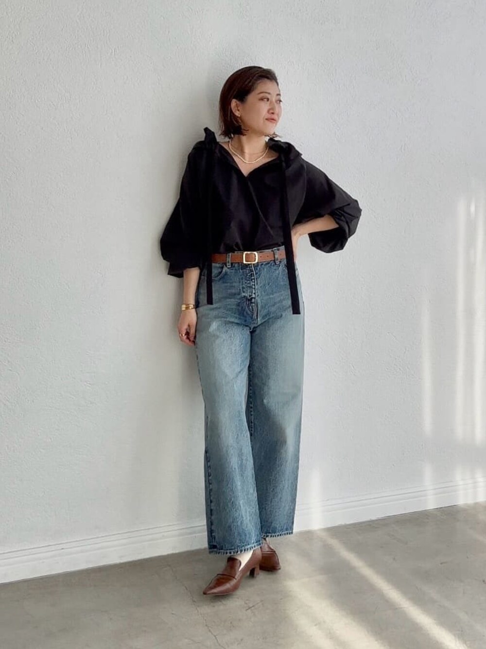 ブラック系のシャツ/ブラウス、ブルー系のデニムパンツ、ブラウン系のローファーを着用したレディースの冬コーディネートの3枚目の写真