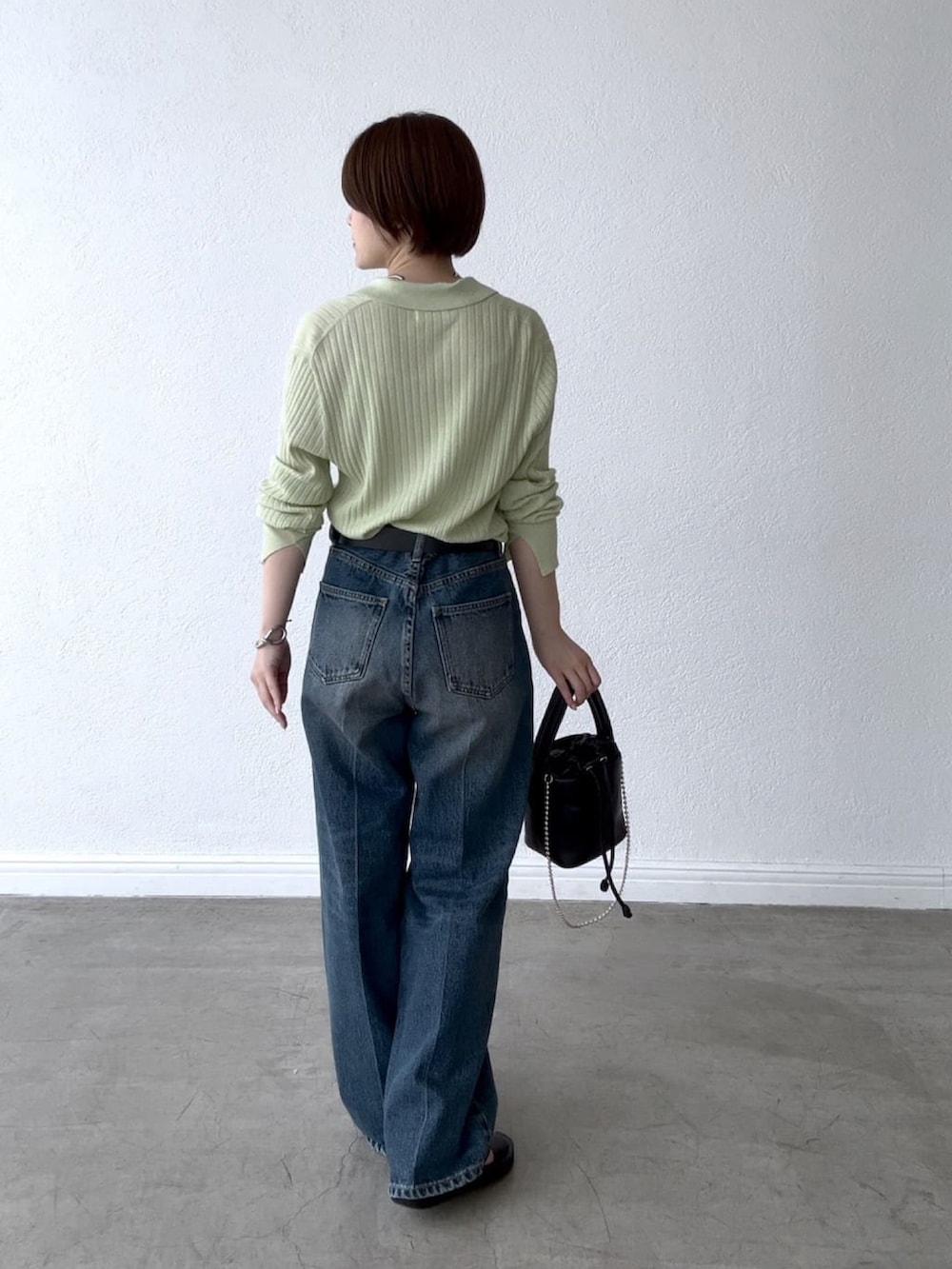 グリーン系のカーディガン/ボレロ、ブルー系のデニムパンツ、ブラック系のハンドバッグを着用したレディースの夏コーディネートの3枚目の写真