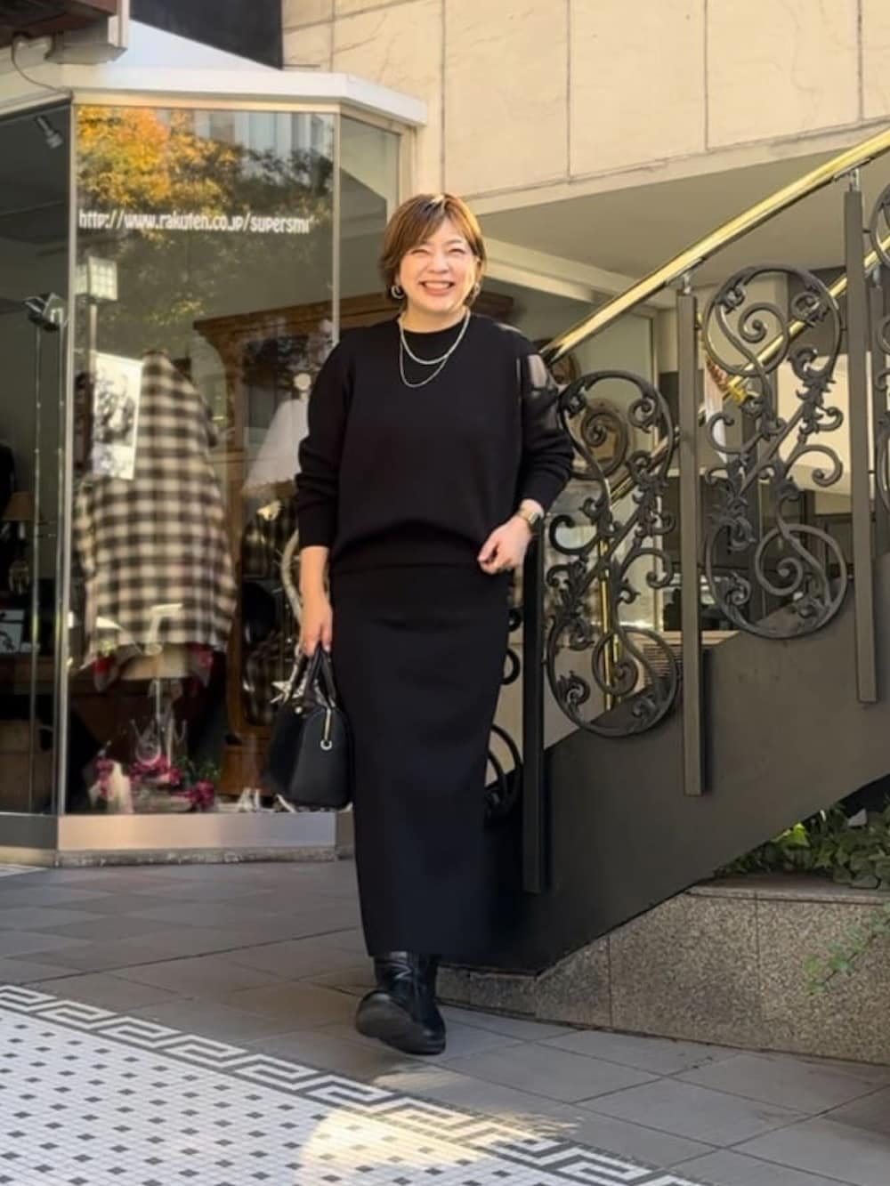 ブルー系のニット/セーター、ブルー系のスカート、ブラック系のボストンバッグを着用したレディースの冬コーディネートの2枚目の写真