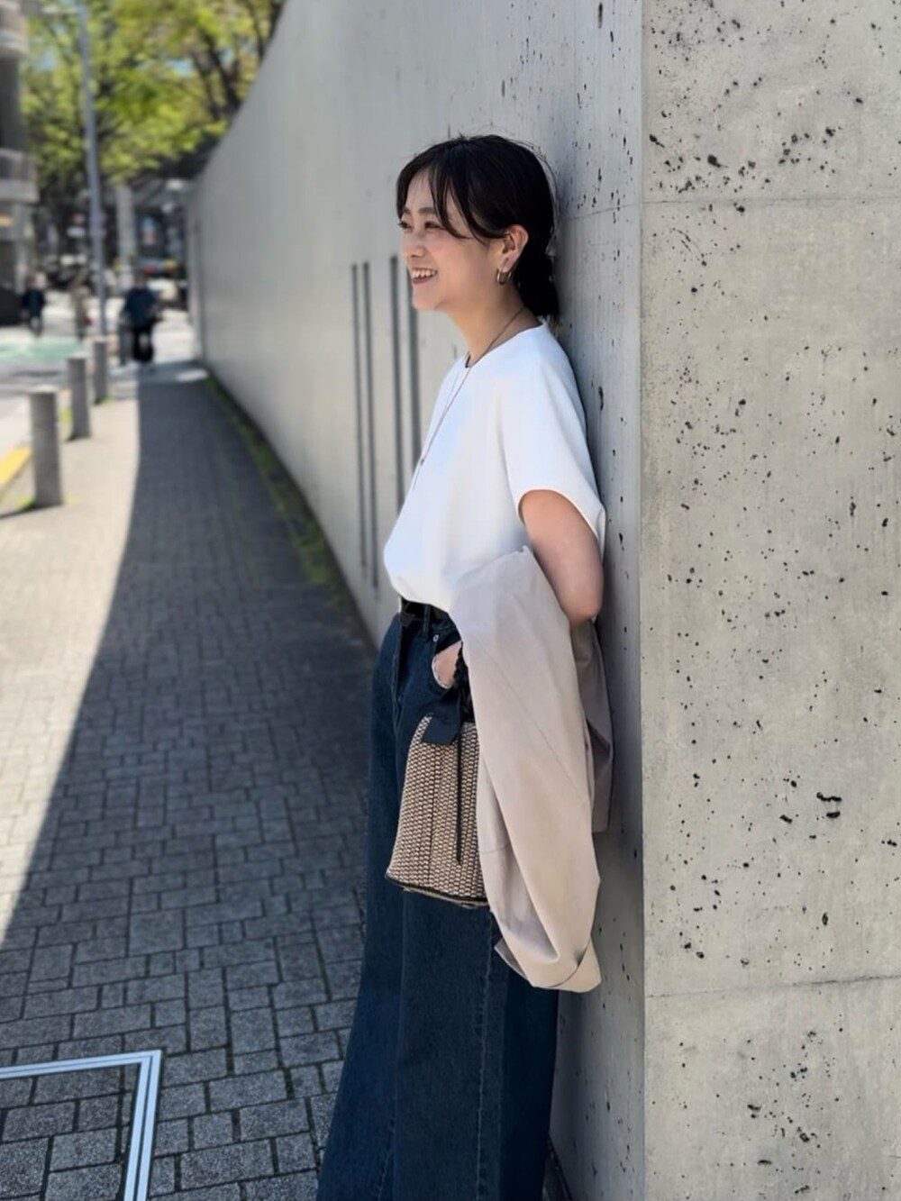 ブルー系のデニムパンツ、ブラック系のハンドバッグ、ブラック系のサンダルを着用したレディースの春コーディネートの5枚目の写真