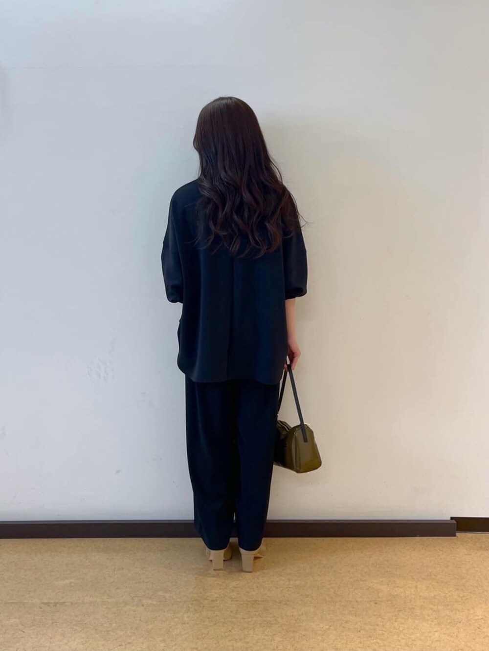 ブラック系のスラックス、ブラック系のTシャツ/カットソー、グリーン系のショルダーバッグを着用したレディースの春コーディネートの3枚目の写真