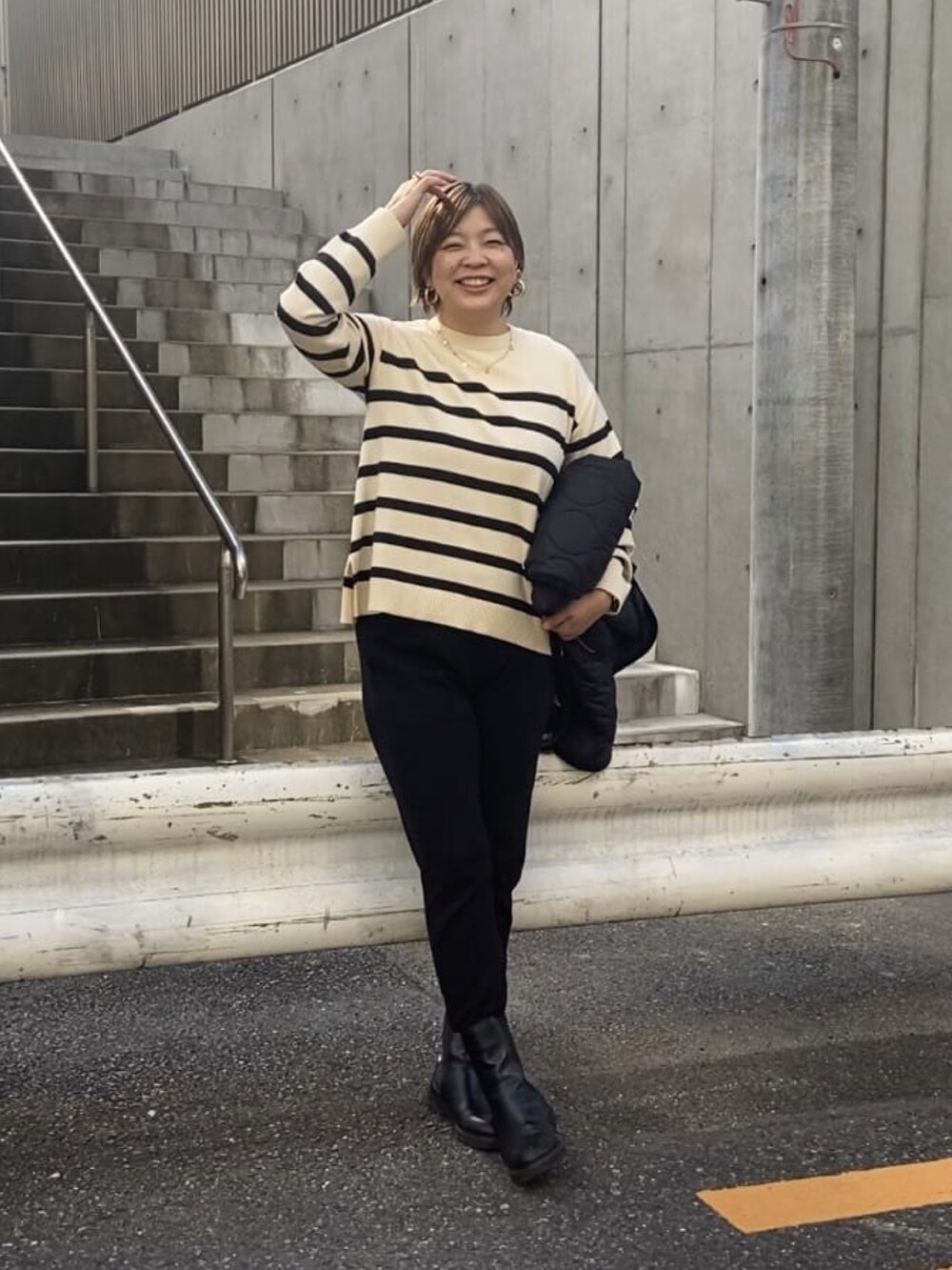 ブラック系のダウンジャケット/コート、ホワイト系のニット/セーター、ブラック系のスウェットパンツを着用したレディースの秋コーディネートの4枚目の写真