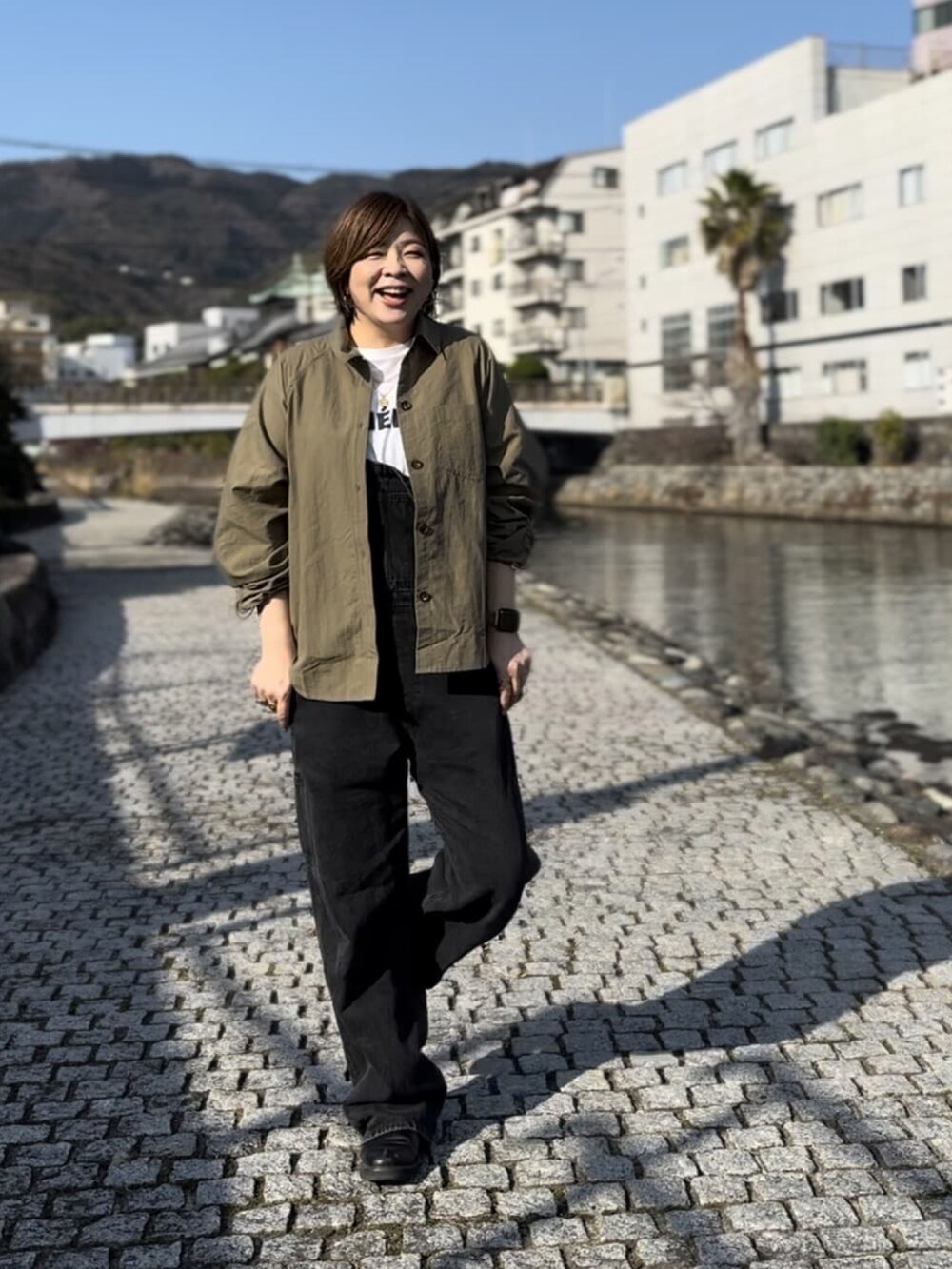 グリーン系のシャツ/ブラウス、ブラック系のサロペット/オーバーオール、ホワイト系のTシャツ/カットソーを着用したレディースの冬コーディネートの3枚目の写真