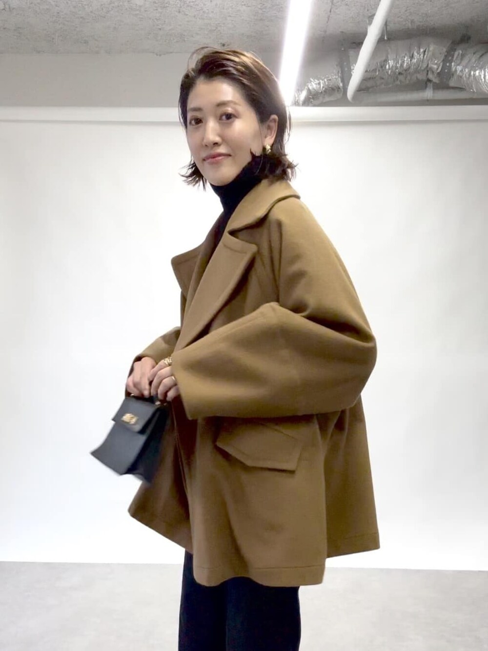 イエロー系のピーコート、ブルー系のデニムパンツ、ブラック系のニット/セーターを着用したレディースの冬コーディネートの4枚目の写真
