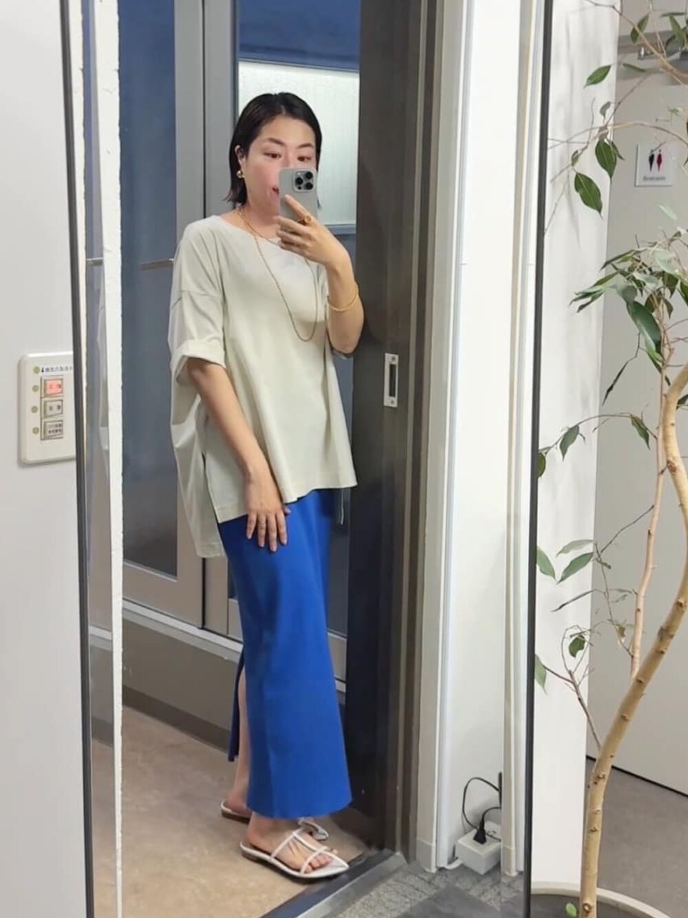 ホワイト系のTシャツ/カットソー、ブルー系のスカート、ホワイト系のサンダルを着用したレディースの春コーディネートの2枚目の写真