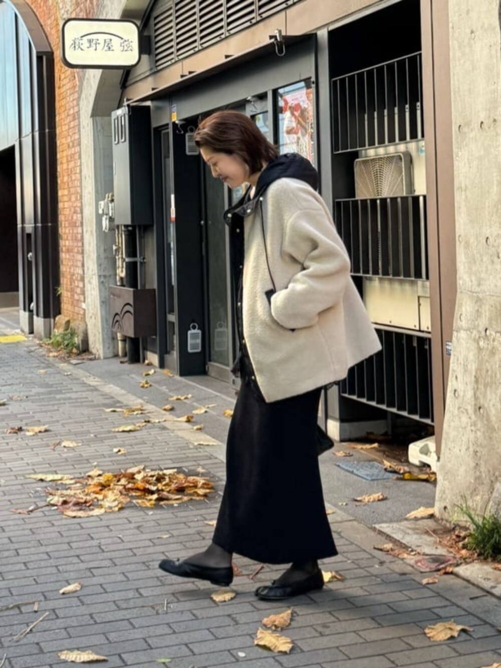 ブラック系のスカート、ブラック系のハンドバッグ、ブラック系のキャミソールを着用したレディースの冬コーディネートの3枚目の写真