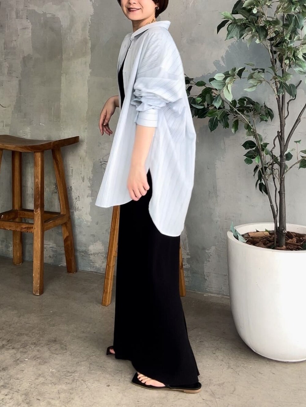 ブラック系のワンピース、ブラック系のサンダル、ブルー系のシャツ/ブラウスを着用したレディースの春コーディネートの2枚目の写真