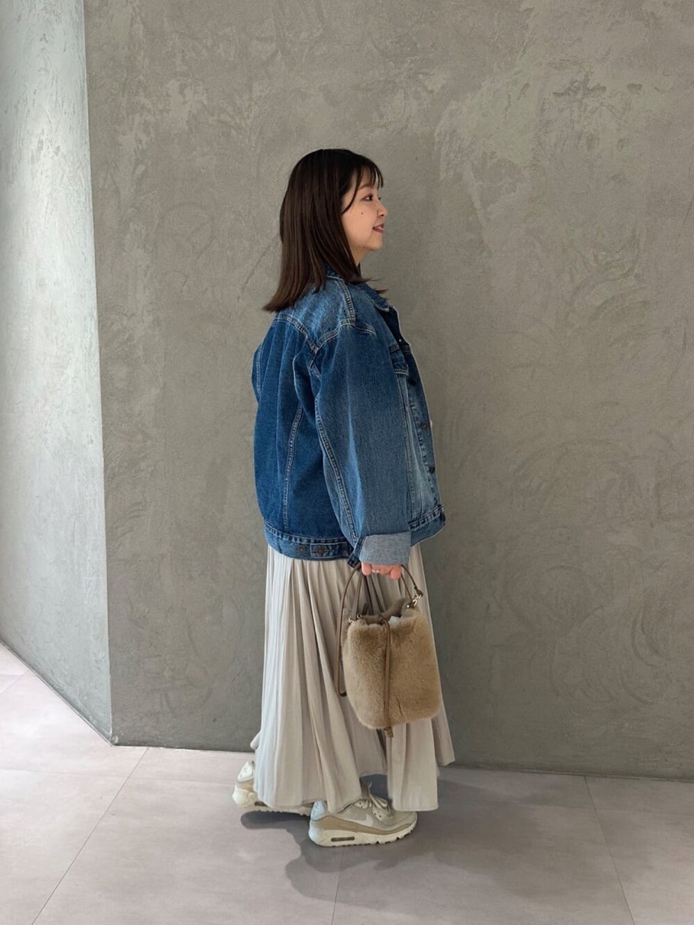 ベージュ系のスカート、ブルー系のデニムジャケット、ベージュ系のハンドバッグを着用したレディースの冬コーディネートの2枚目の写真