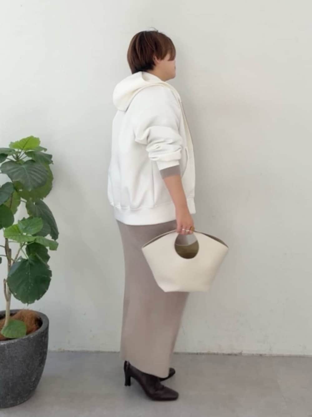 ホワイト系のハンドバッグ、ホワイト系のパーカー、ブラウン系のニット/セーターを着用したレディースの冬コーディネートの2枚目の写真