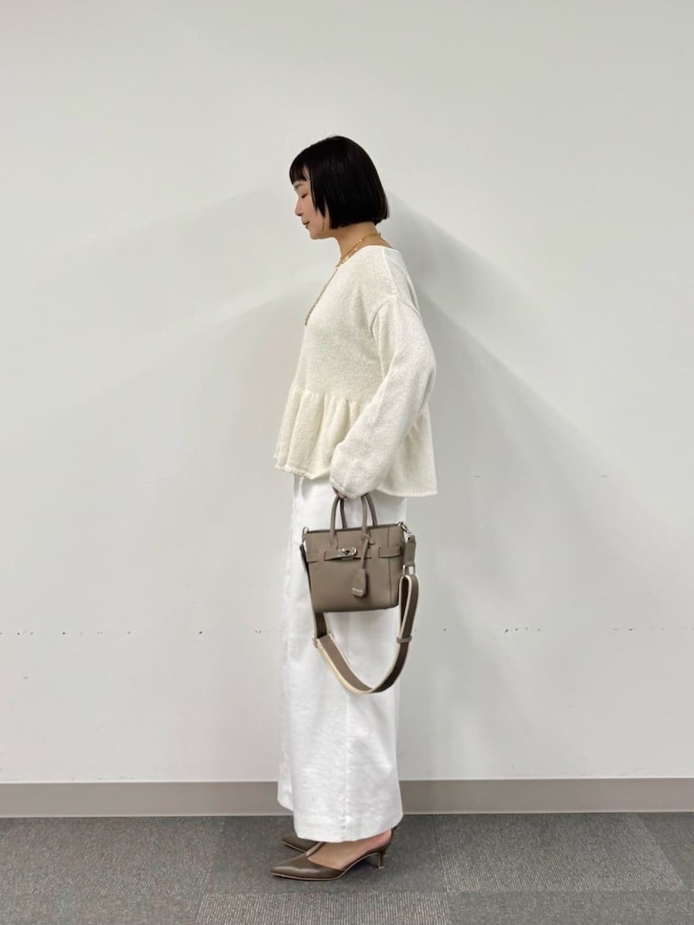 ホワイト系のニット/セーター、グレー系のトートバッグ、ホワイト系のスカートを着用したレディースの冬コーディネートの2枚目の写真