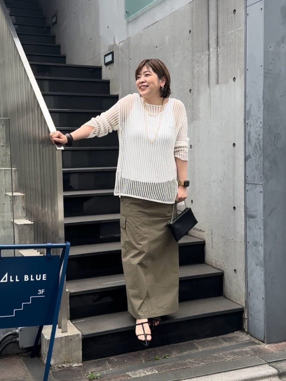 ホワイト系のニット/セーター、ブラック系のスカート、ブラック系のサンダルを着用したレディースの春コーディネートの3枚目の写真