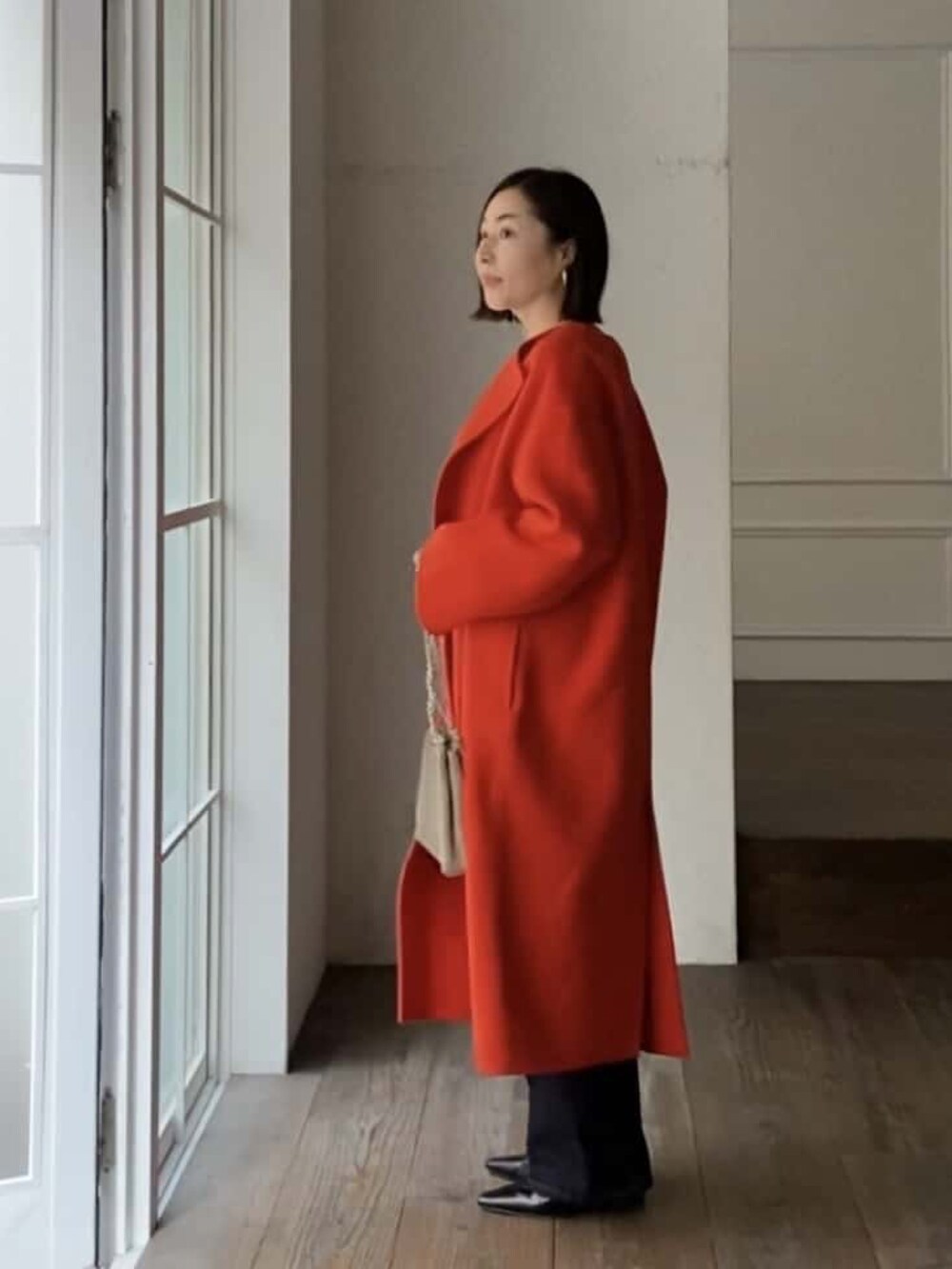 ブルー系のデニムパンツ、ブラック系のローファー、ベージュ系のショルダーバッグを着用したレディースの冬コーディネートの2枚目の写真