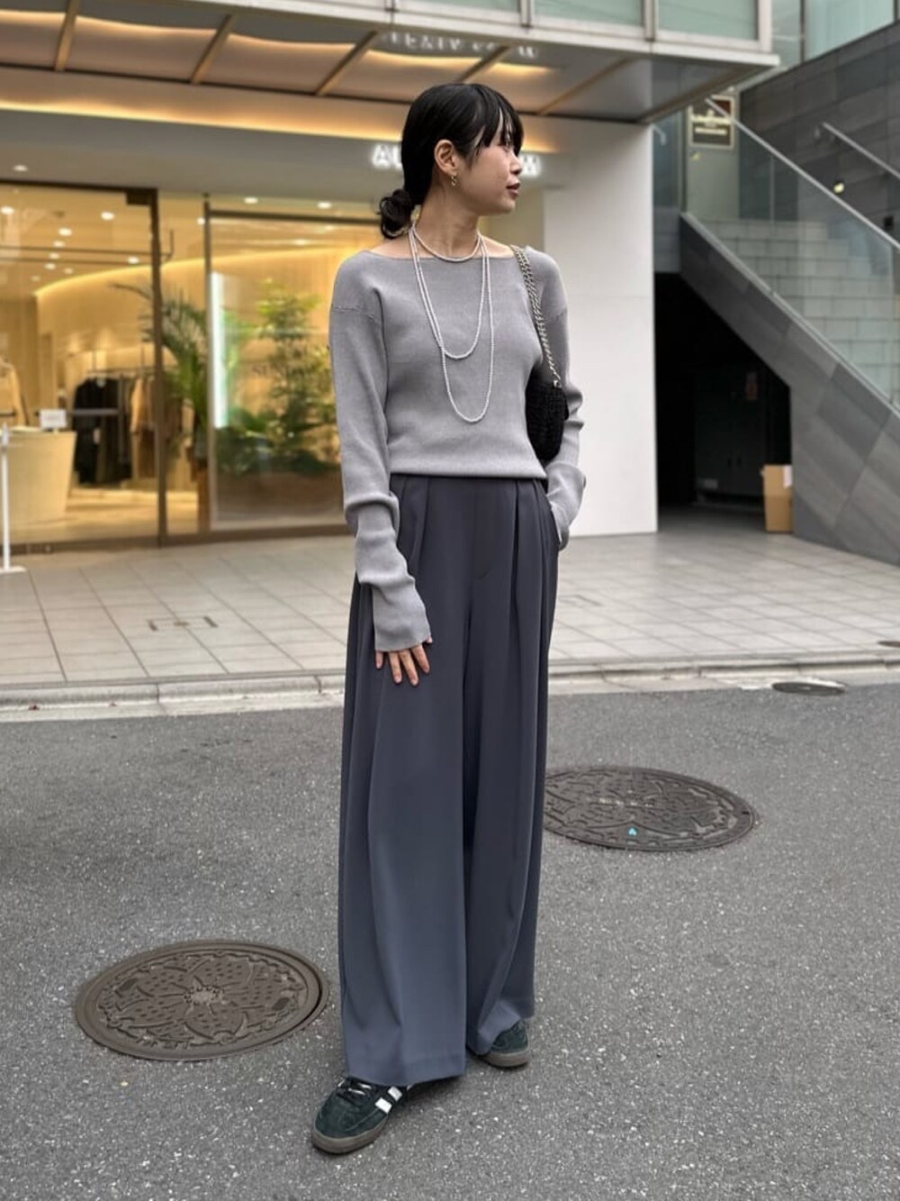 グレー系のニット/セーター、ブラック系のマウンテンパーカー、グレー系のスラックスを着用したレディースの冬コーディネートの2枚目の写真