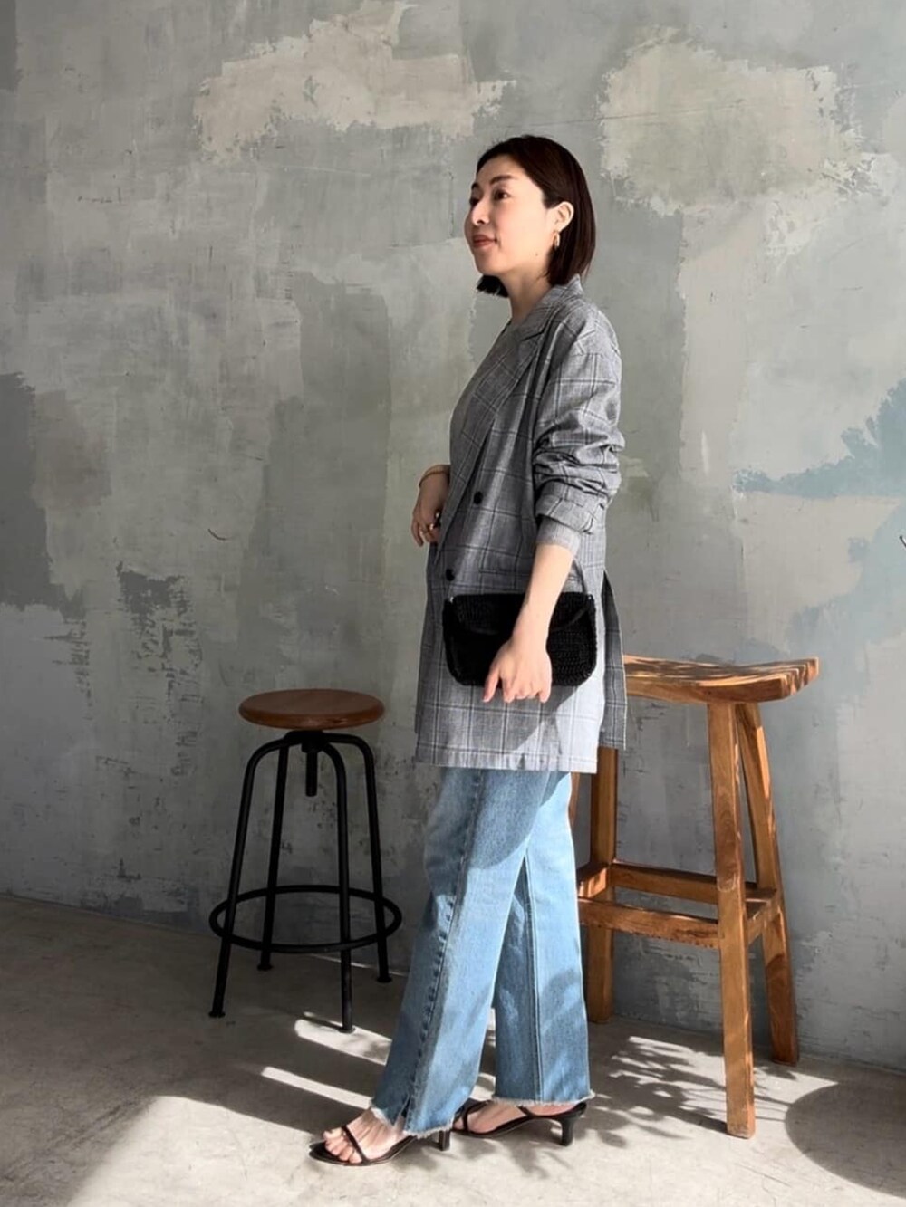 グレー系のテーラードジャケット、ブラック系のショルダーバッグ、ブルー系のデニムパンツを着用したレディースの春コーディネートの2枚目の写真