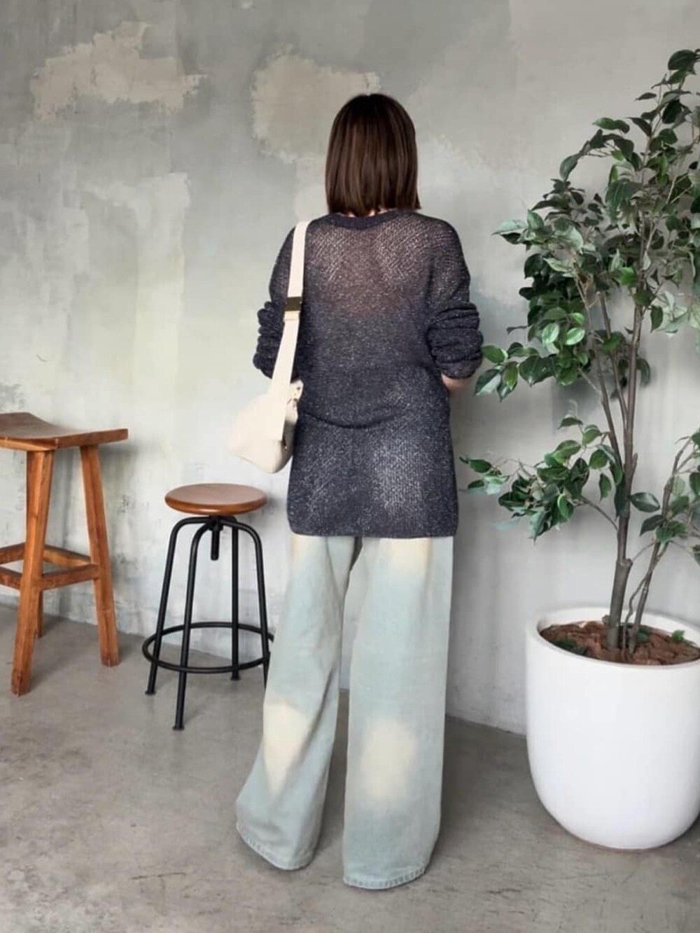 ブルー系のデニムパンツ、ブルー系のニット/セーター、ホワイト系のボディバッグ/ウエストポーチを着用したレディースの夏コーディネートの3枚目の写真