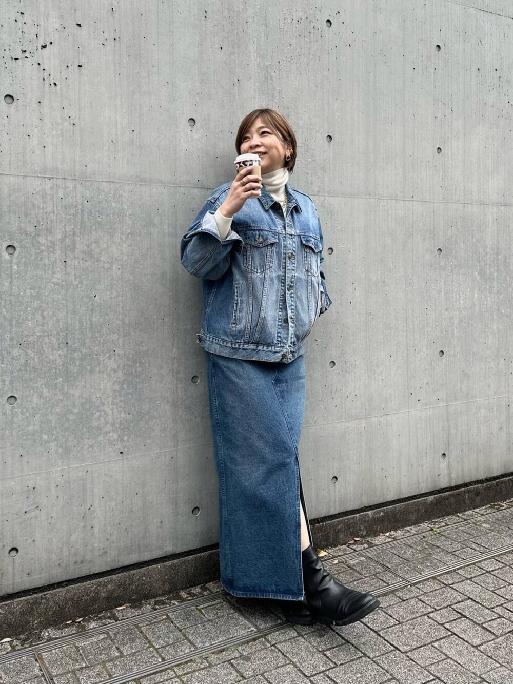 ブルー系のジャンパースカート、ブラック系のブーツを着用したレディースの冬コーディネートの2枚目の写真