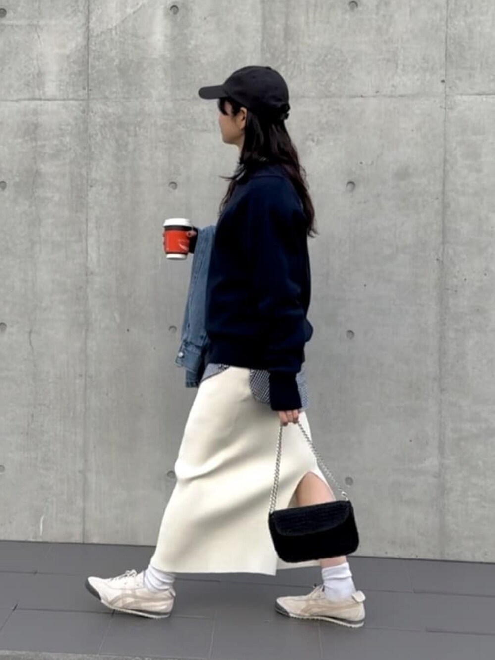 ブルー系のニット/セーター、ブラック系のシャツ/ブラウス、ホワイト系のスカートを着用したレディースの春コーディネートの2枚目の写真