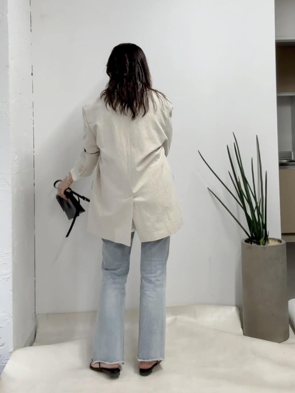 ベージュ系のテーラードジャケット、ホワイト系のニット/セーター、ブルー系のデニムパンツを着用したレディースの冬コーディネートの3枚目の写真