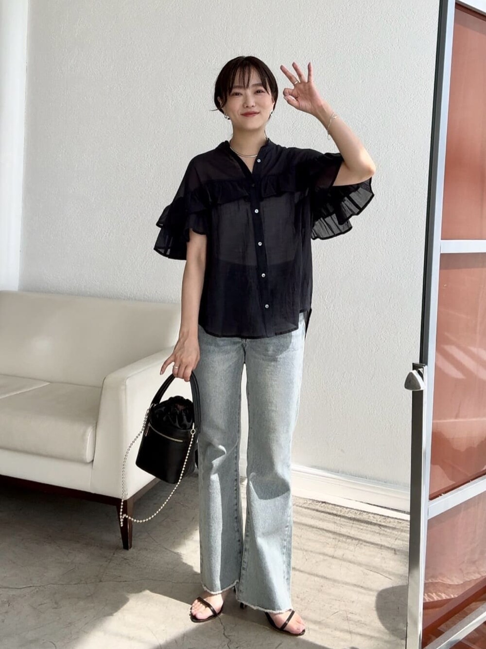 ブラック系のシャツ/ブラウス、ブルー系のデニムパンツ、ブラック系のサンダルを着用したレディースの夏コーディネートの2枚目の写真